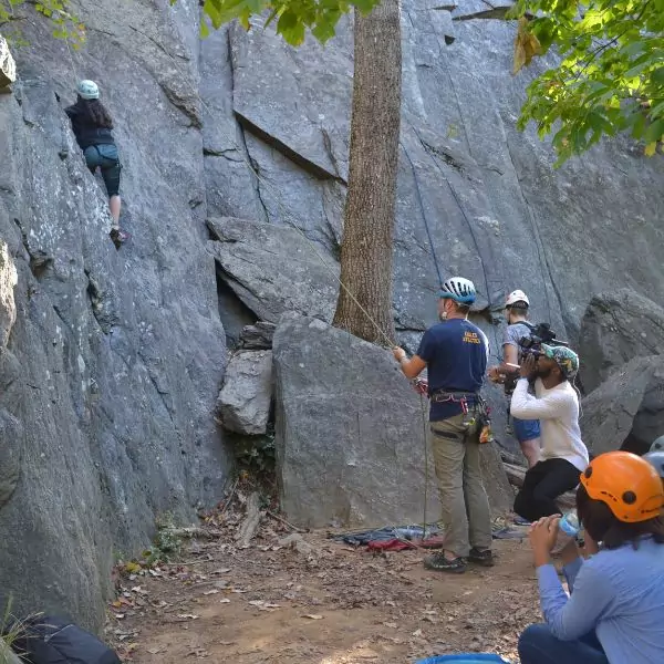 Students engaging in an outdoor rock climbing activity under the supervision of an instructor.